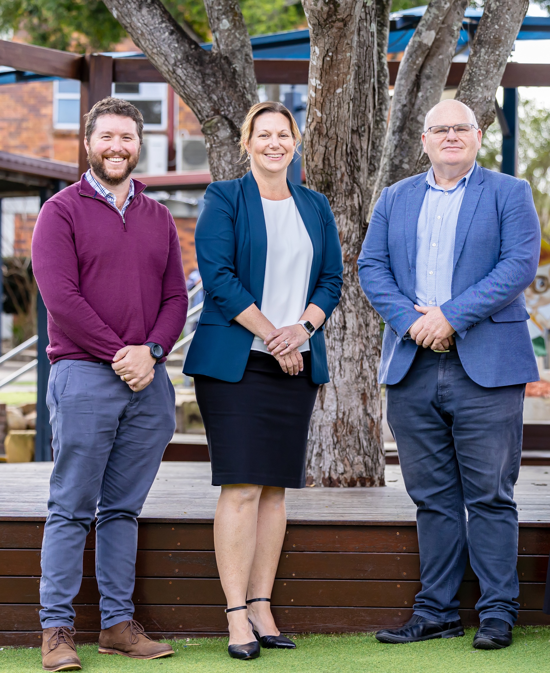 School leadership staff standing together outdoors on campus in front of trees and school buildings